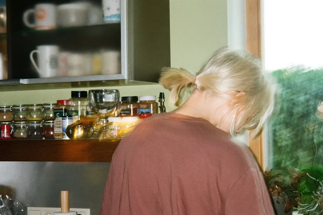 Mature adult examining supplement bottle in modern kitchen with fresh vegetables and fish, representing evidence-based brain 