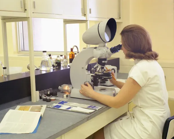 Scientist examining nootropic supplement bottles and pills in laboratory with microscope, conducting rigorous scientific anal
